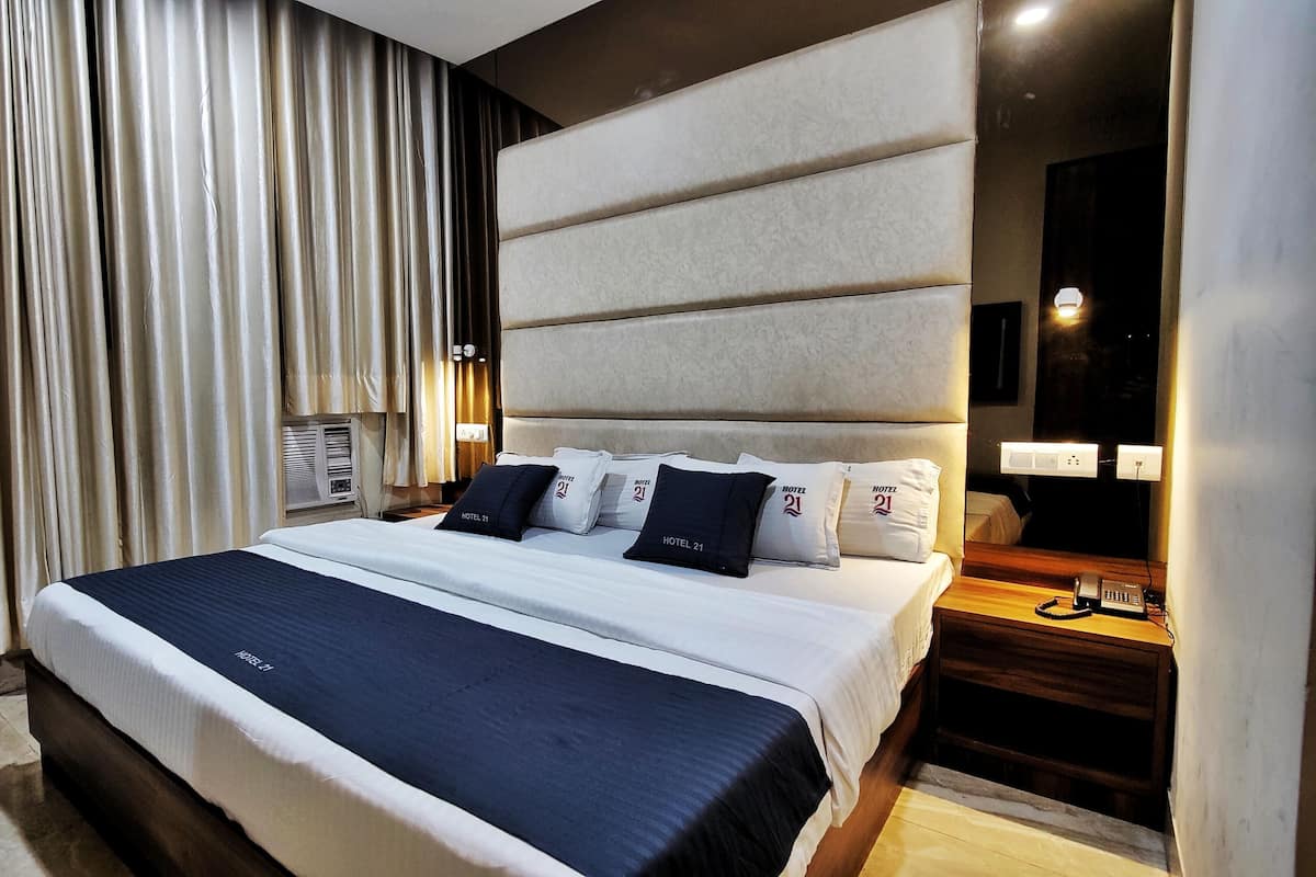 Ein Hotelzimmer mit einem großen Bett, einem Nachttisch mit Telefon und einer Wandleuchte.