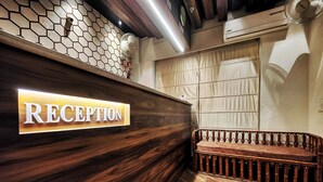 A reception desk with a sign labeled "RECEPTION" and a wooden bench with a metal railing. - Hotel 21 Chandigarh (Chandigarh)