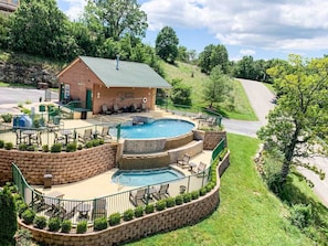A pool area with a stone wall, lounge chairs, and a building with a green roof.