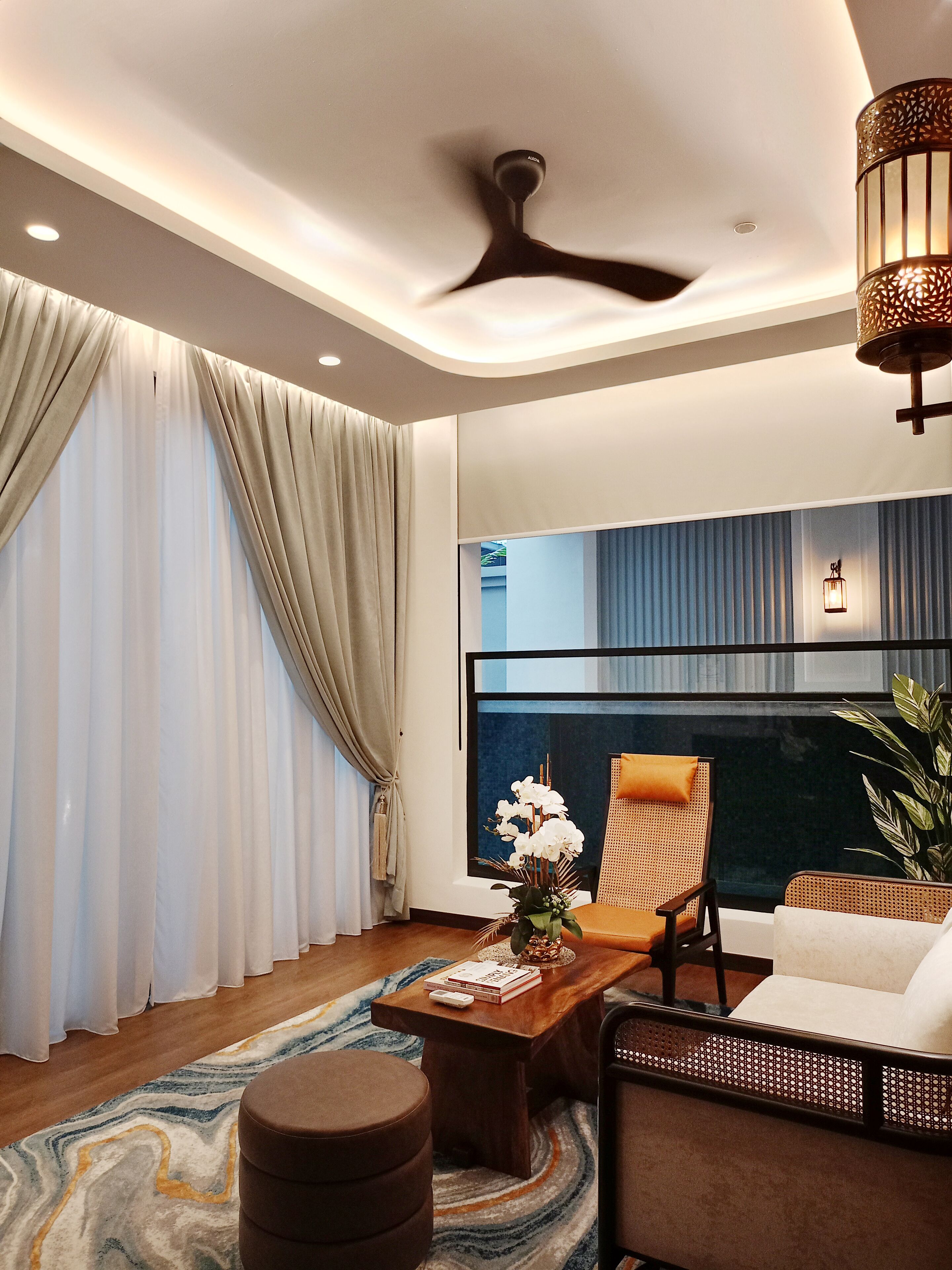 A modern living room with a ceiling fan, a large window with curtains, a sofa, a coffee table, and a plant.