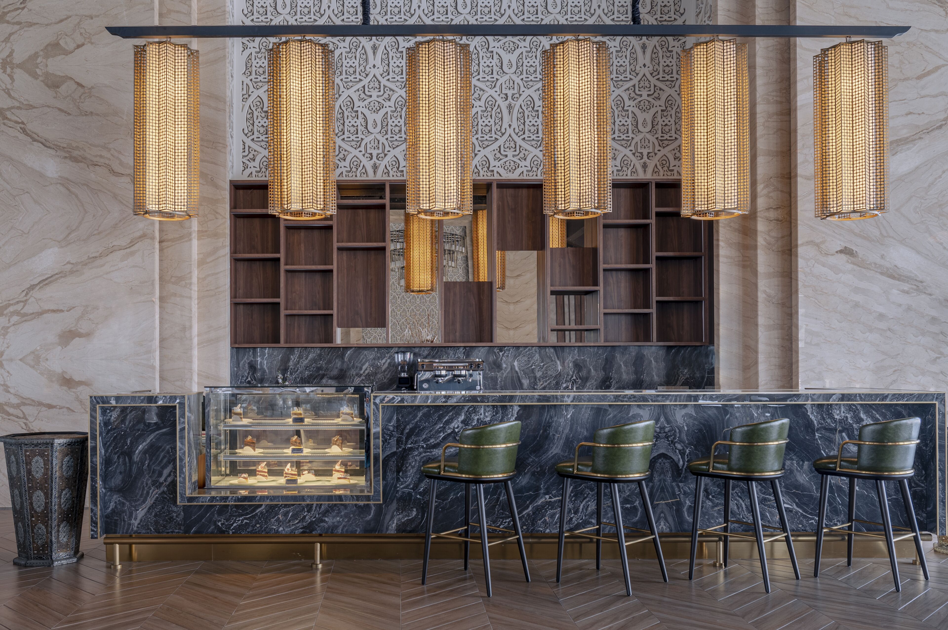 Zona bar moderna con bancone in marmo, diversi sgabelli e luci decorative a sospensione.
