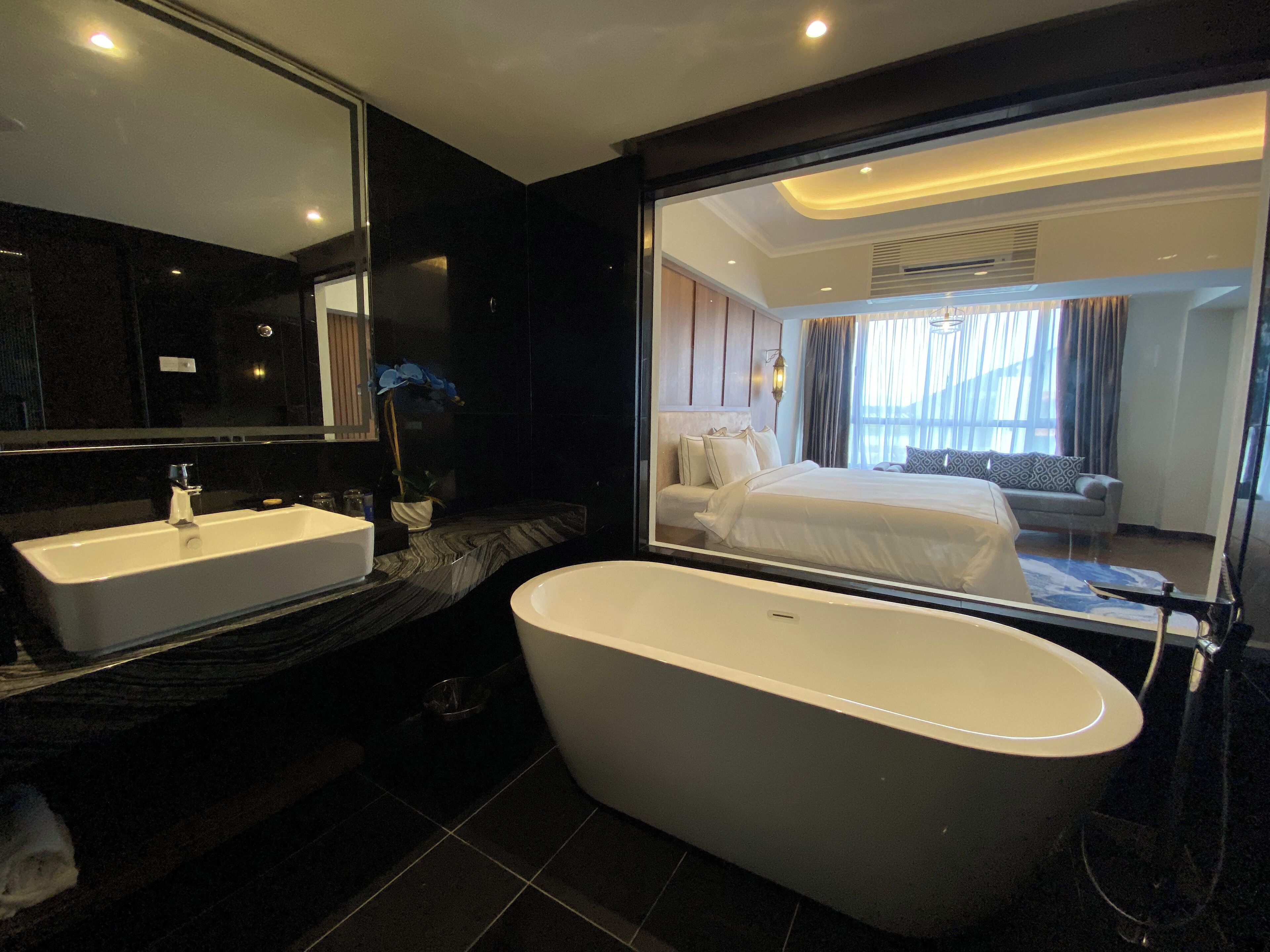 A modern bathroom with a freestanding bathtub, a large mirror, and a vanity with a sink.