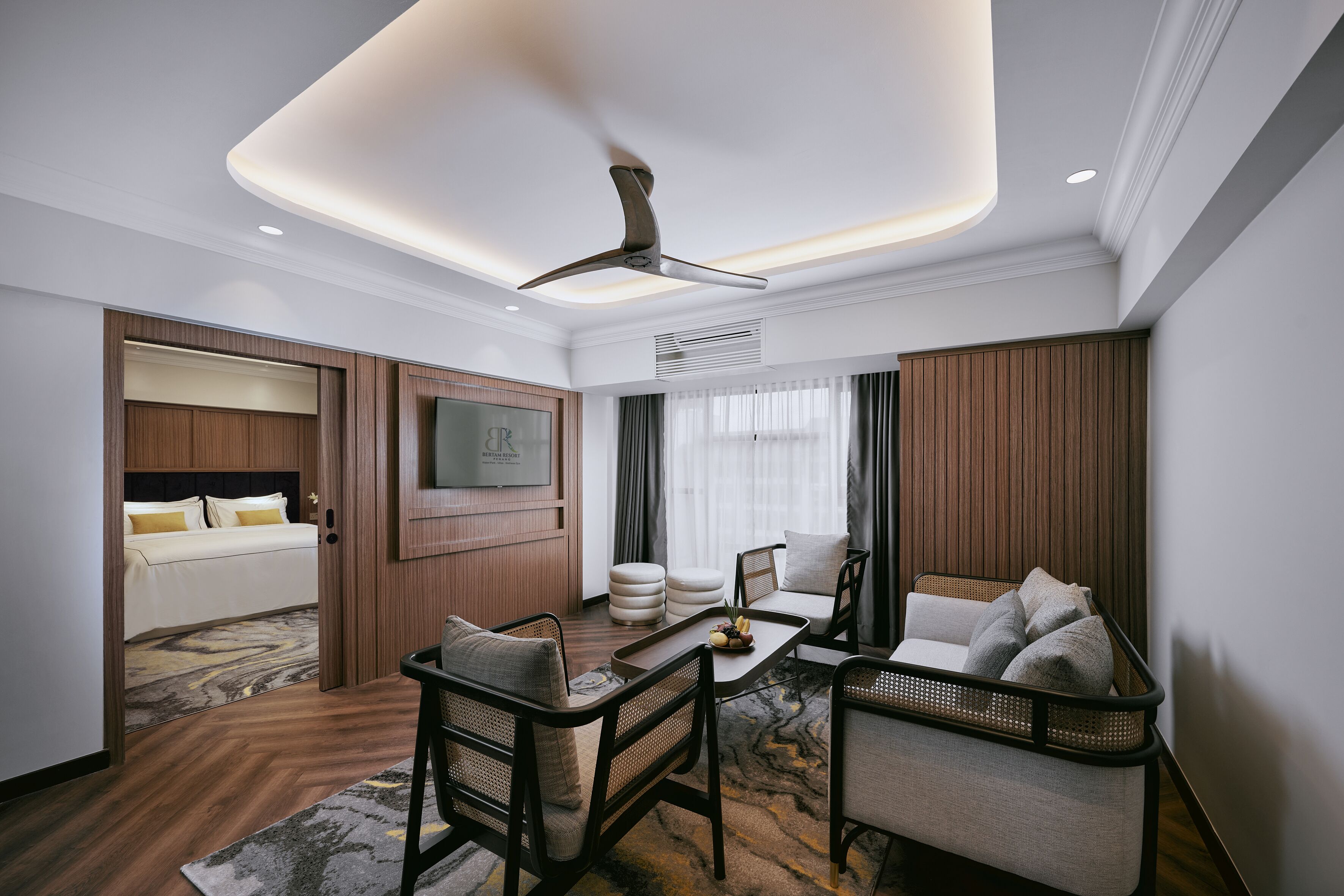 Una habitación de hotel moderna con una cama, una zona de estar con una mesa y un ventilador de techo.