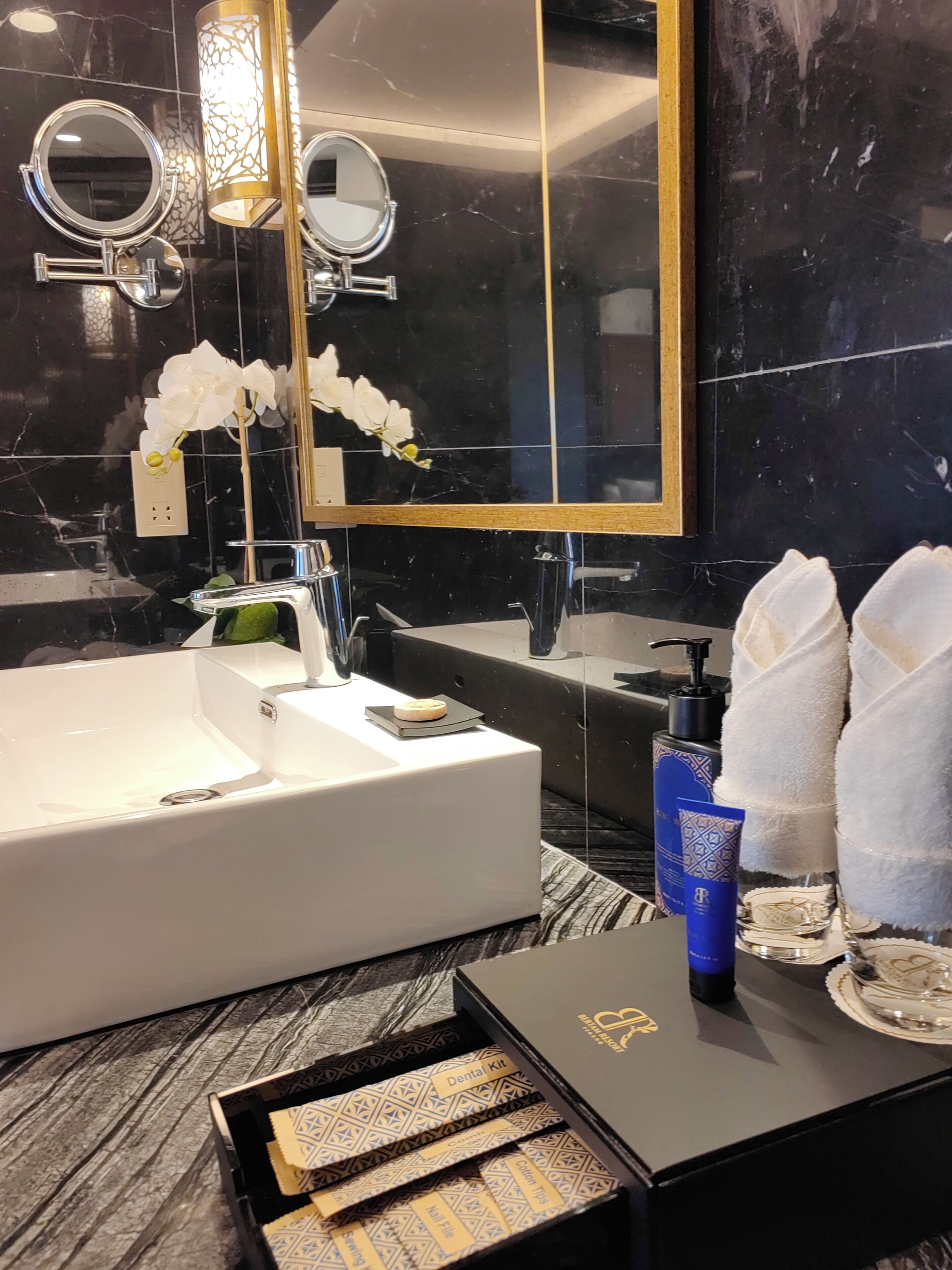 Une salle de bain moderne avec une grande baignoire, deux miroirs ronds, un meuble-lavabo et un grand miroir. Des serviettes et des articles de toilette sont posés sur le meuble-lavabo.