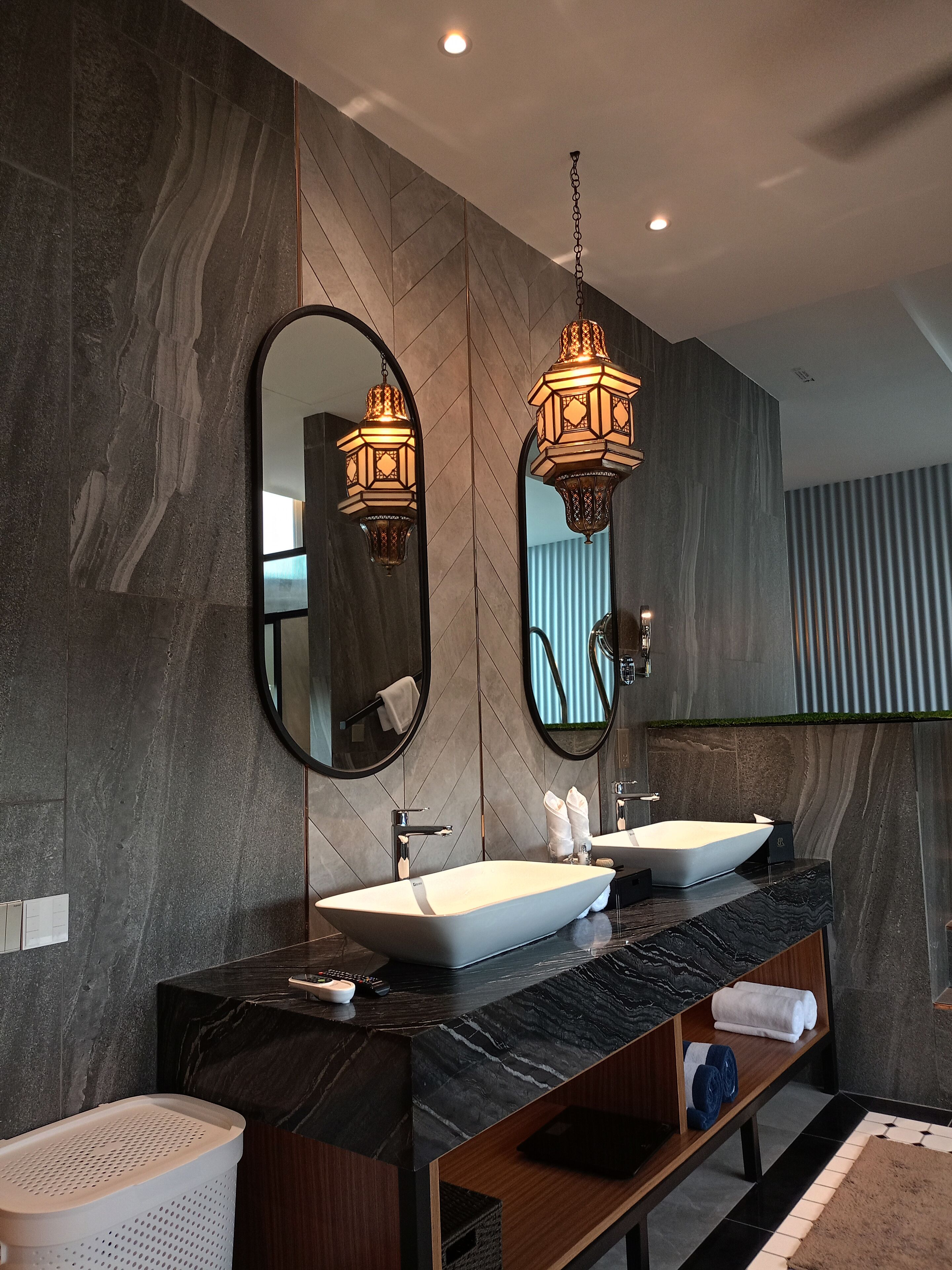 Un baño moderno con dos lavamanos, un espejo grande e iluminación decorativa.