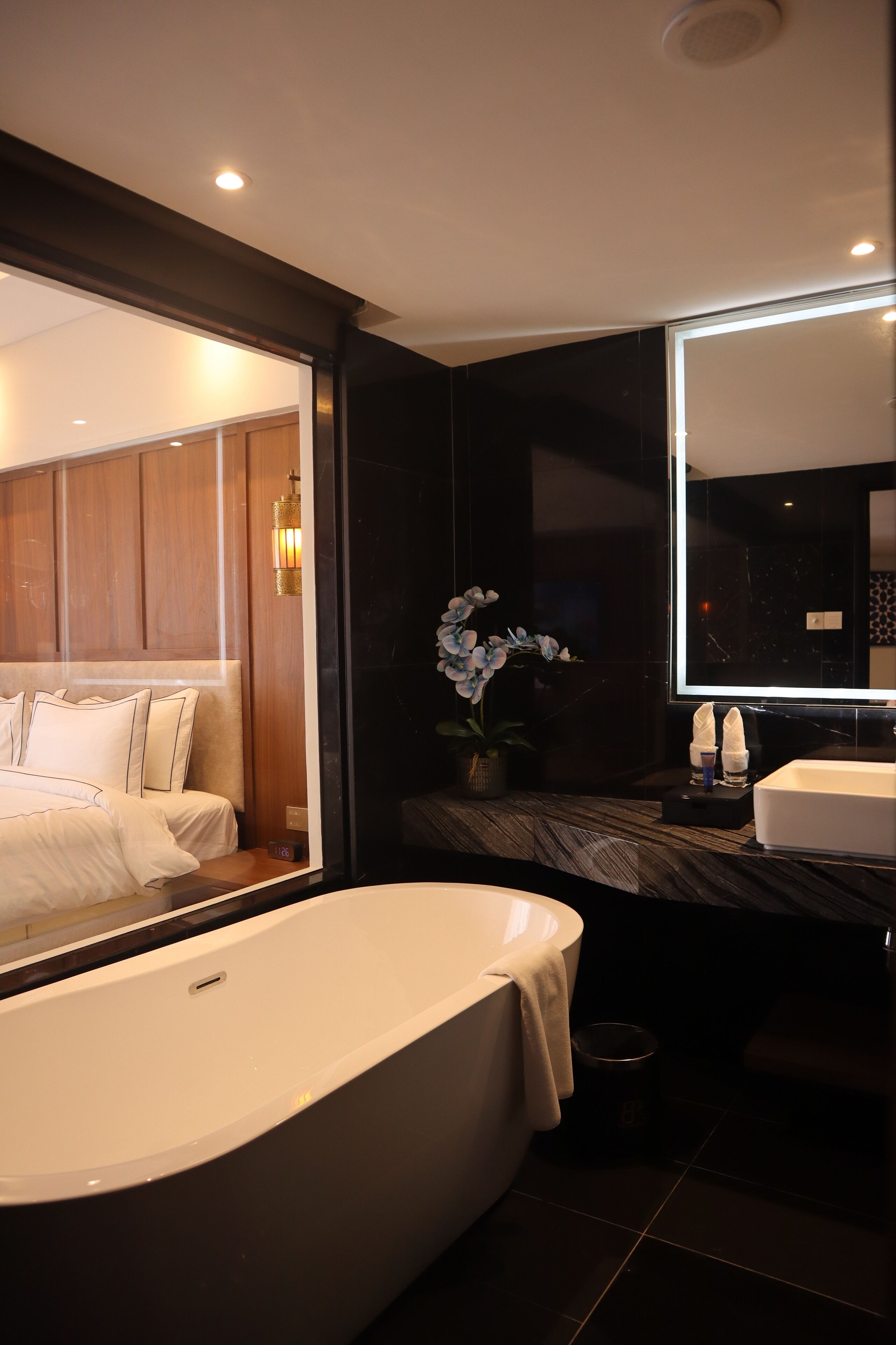 Un baño moderno con una bañera grande, un espejo y un mueble de tocador de madera.