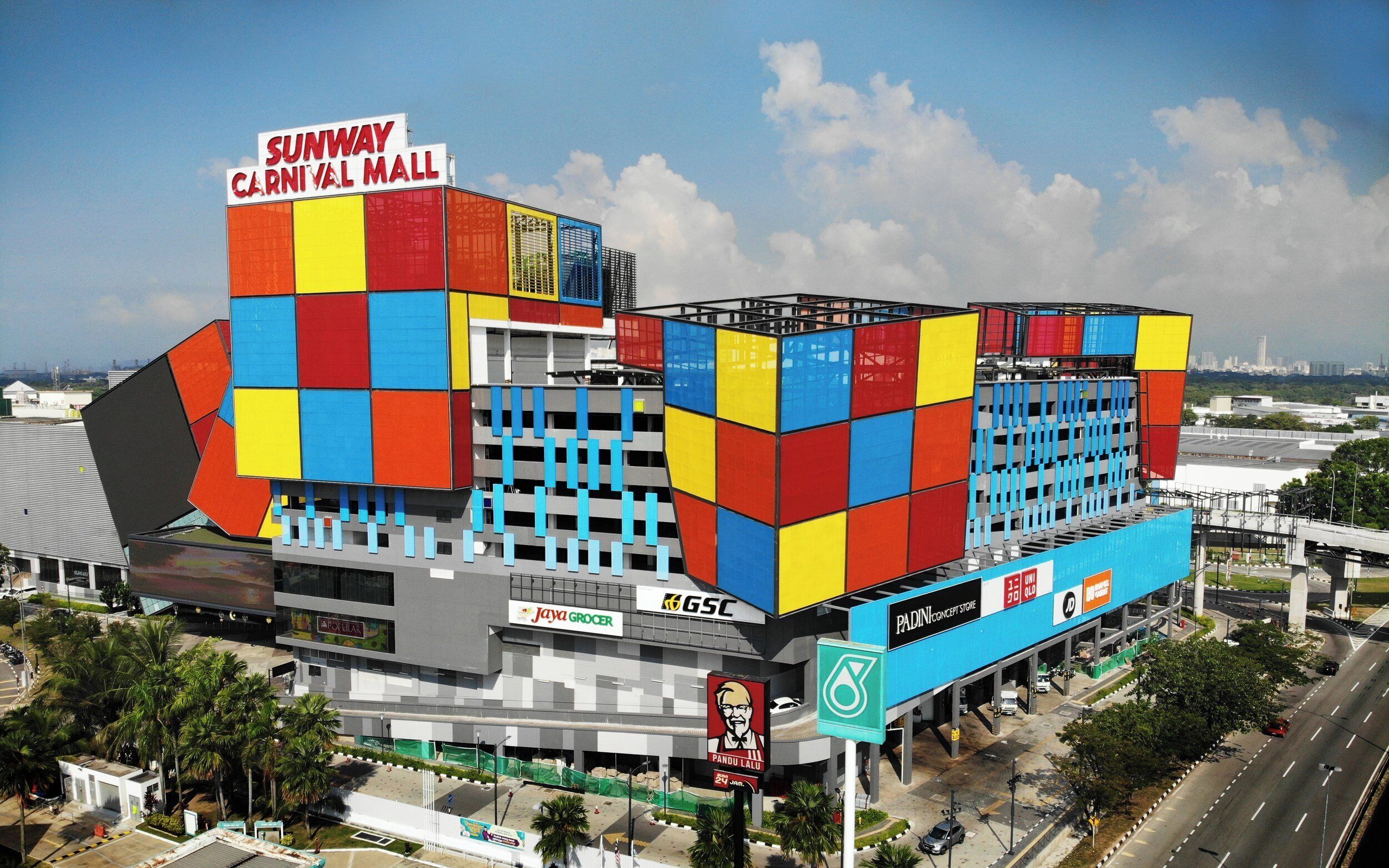 A multi-story building with a colorful facade, a prominent sign for Sunway Carnival Mall, and various commercial signs including Jaya Grocer and GSC.