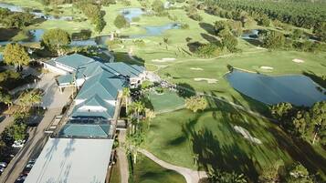 Vista aérea de un campo de golf con varios estanques, un club de campo y un aparcamiento.