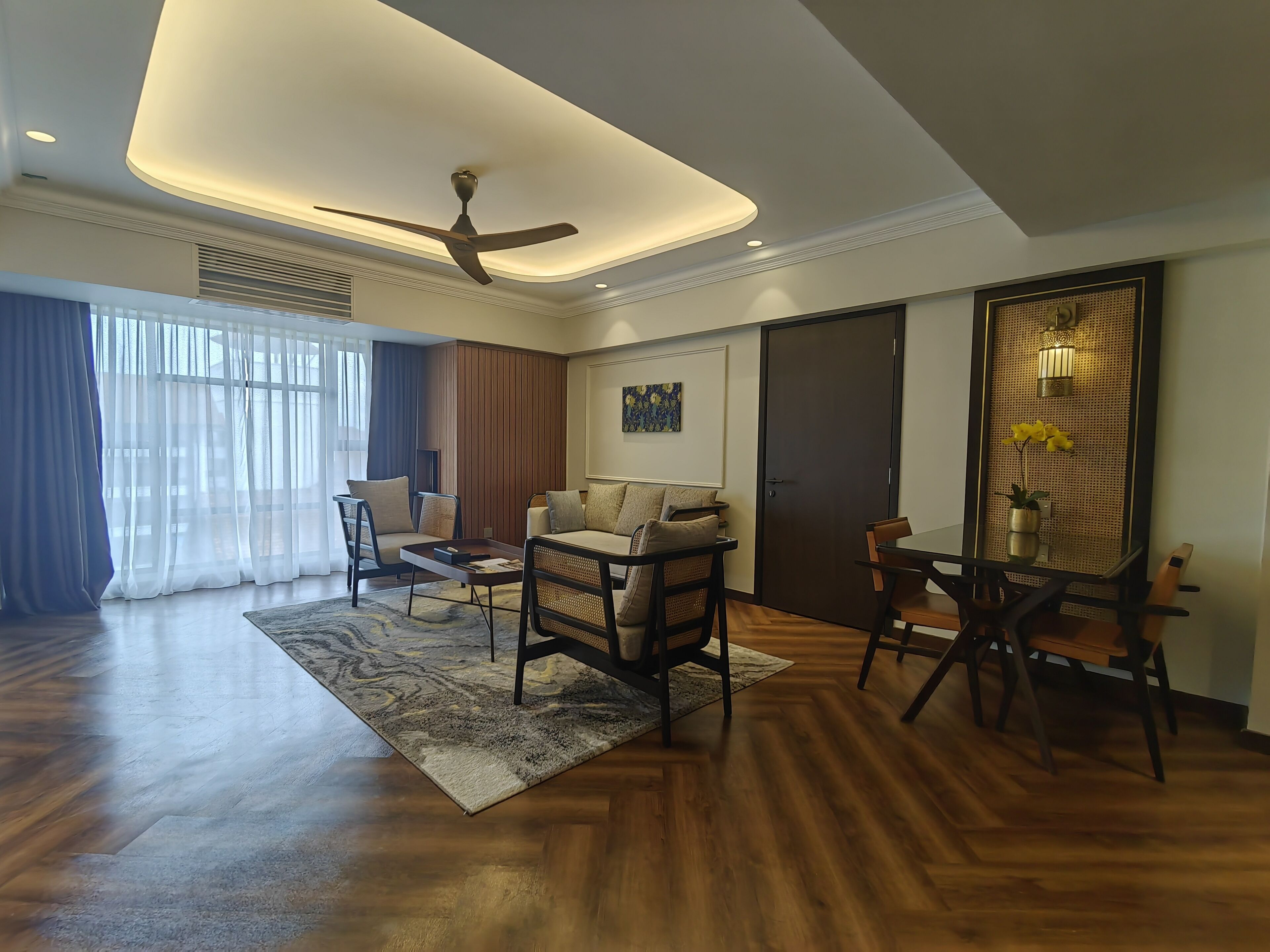 A spacious living room with a ceiling fan, a sofa set, a coffee table, and a dining table with chairs.