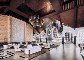 A spacious lobby with a high ceiling, modern furniture, and a large chandelier.