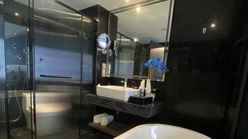 A modern bathroom with a large bathtub, a glass shower enclosure, and a vanity with a mirror.