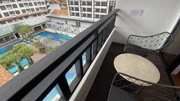 En balkon med udsigt over en swimmingpool og hotelbygninger.