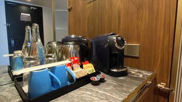 En køkkenbordplade med en kaffemaskine, en bakke med krydderier og et spejl over.