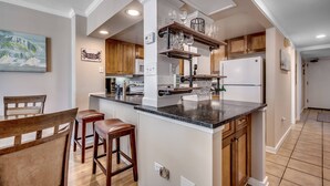 A modern kitchen with wooden cabinets, a central island, and a bar area with stools.