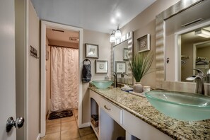A bathroom with two glass sinks, a large mirror, and a shower curtain.