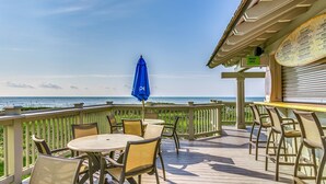 A deck with a table and chairs, a blue umbrella, and a menu board.