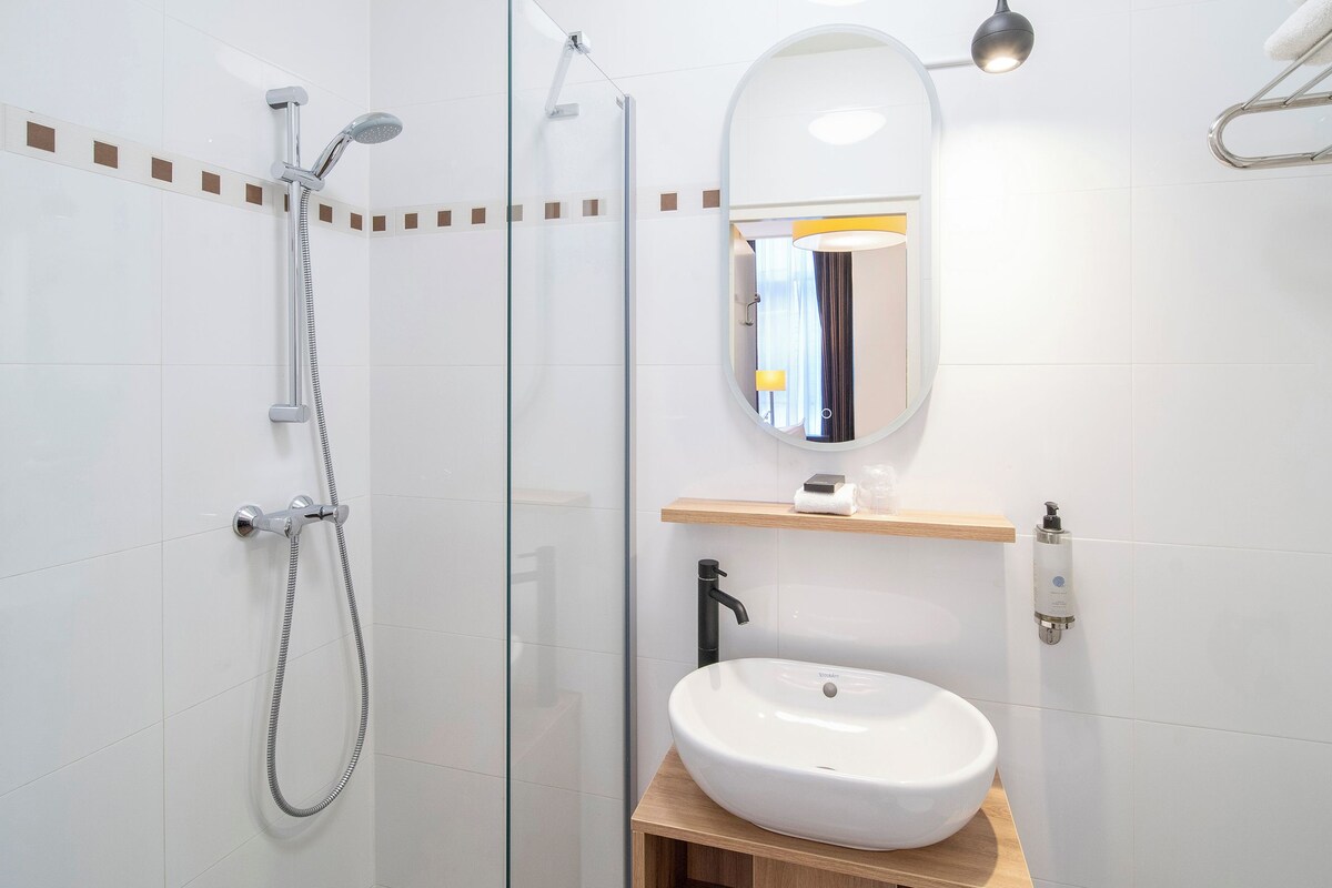 A modern bathroom with a glass-enclosed shower, a white sink, and a wooden vanity.