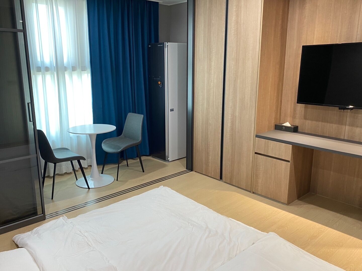 Habitación de hotel con cama, escritorio, silla, televisión y minibar.