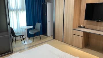 Habitación de hotel con cama, escritorio, silla, televisión y minibar.