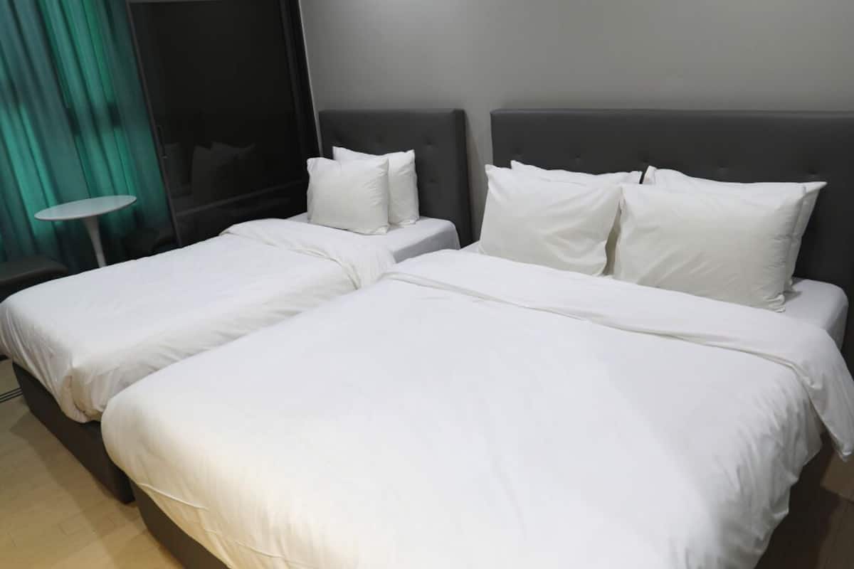 Ein Hotelzimmer mit zwei Betten, jeweils mit weißer Bettwäsche und Kopfteilen.