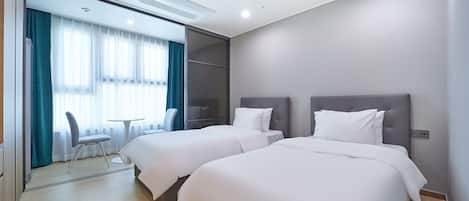 A hotel room with two beds, a desk, and a chair.