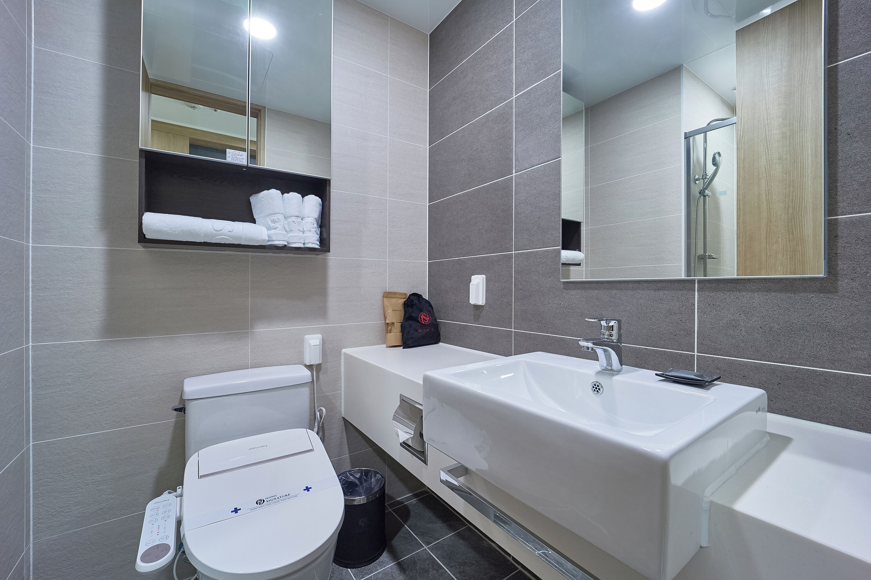 A modern bathroom with a toilet, sink, and mirror.