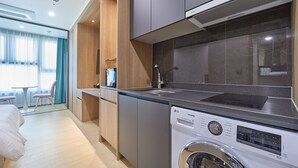 A compact hotel room with a kitchenette, a washing machine, a bed, and a small seating area with a table and chairs. - Jeonju Signature Hotel (Jeonju)