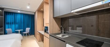 A modern kitchen with a built-in dishwasher, a stove, and a sink. There is a small table and two chairs in the adjacent room.