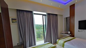 A hotel room with two beds, a TV, a small table with toiletries, and a balcony with curtains. - DERA Resort & Spa- Cox's Bazar (Cox's Bazar)
