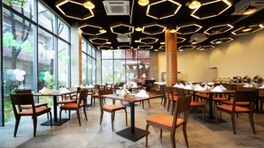 A spacious restaurant with hexagonal ceiling lights, large windows, and wooden tables and chairs. - DERA Resort & Spa- Cox's Bazar (Cox's Bazar)