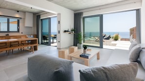 Ein modernes Wohnzimmer mit einem großen Schiebeglasfenster, das auf einen Balkon mit Meerblick führt.