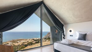 Ein Schlafzimmer mit einem großen Fenster und Blick auf eine Küstenlandschaft.