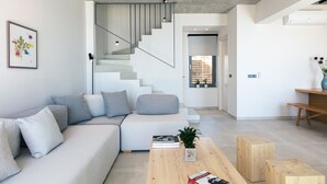 Ein modernes Wohnzimmer mit einem grauen Sofa, einem Holztisch und einer Treppe, die in einen anderen Raum führt.