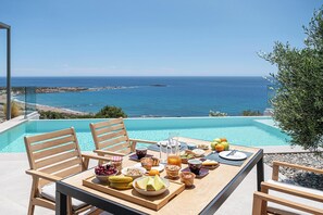 Une table à manger dressée pour le petit-déjeuner, avec vue sur l’océan.