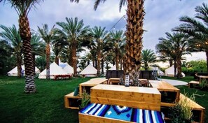 Guests can relax on the central platform amidst lush greenery and palm trees.