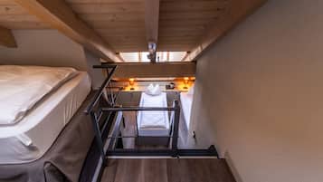 Una habitación pequeña con literas, una kitchenette y techo de madera.