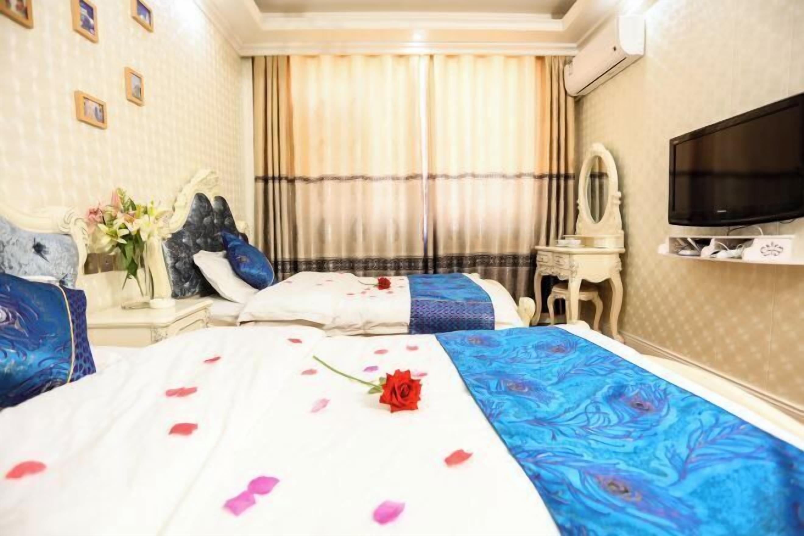 Ett hotellrum med två sängar, en tv, en spegel och en vas med blommor.