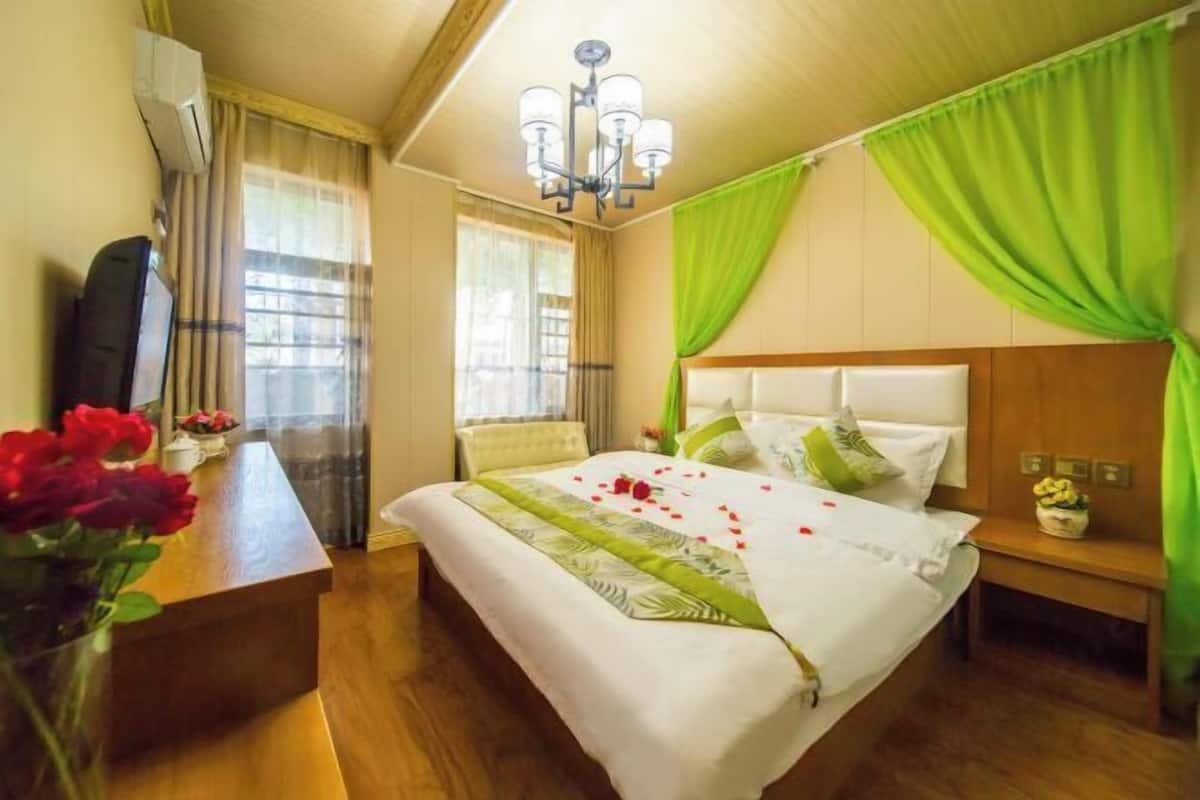 A hotel room with a bed, a desk, a chair, a TV, and a window with curtains.