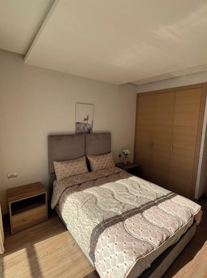 Une chambre à coucher comprenant un lit, une table de chevet, une armoire et une œuvre d’art accrochée au mur.