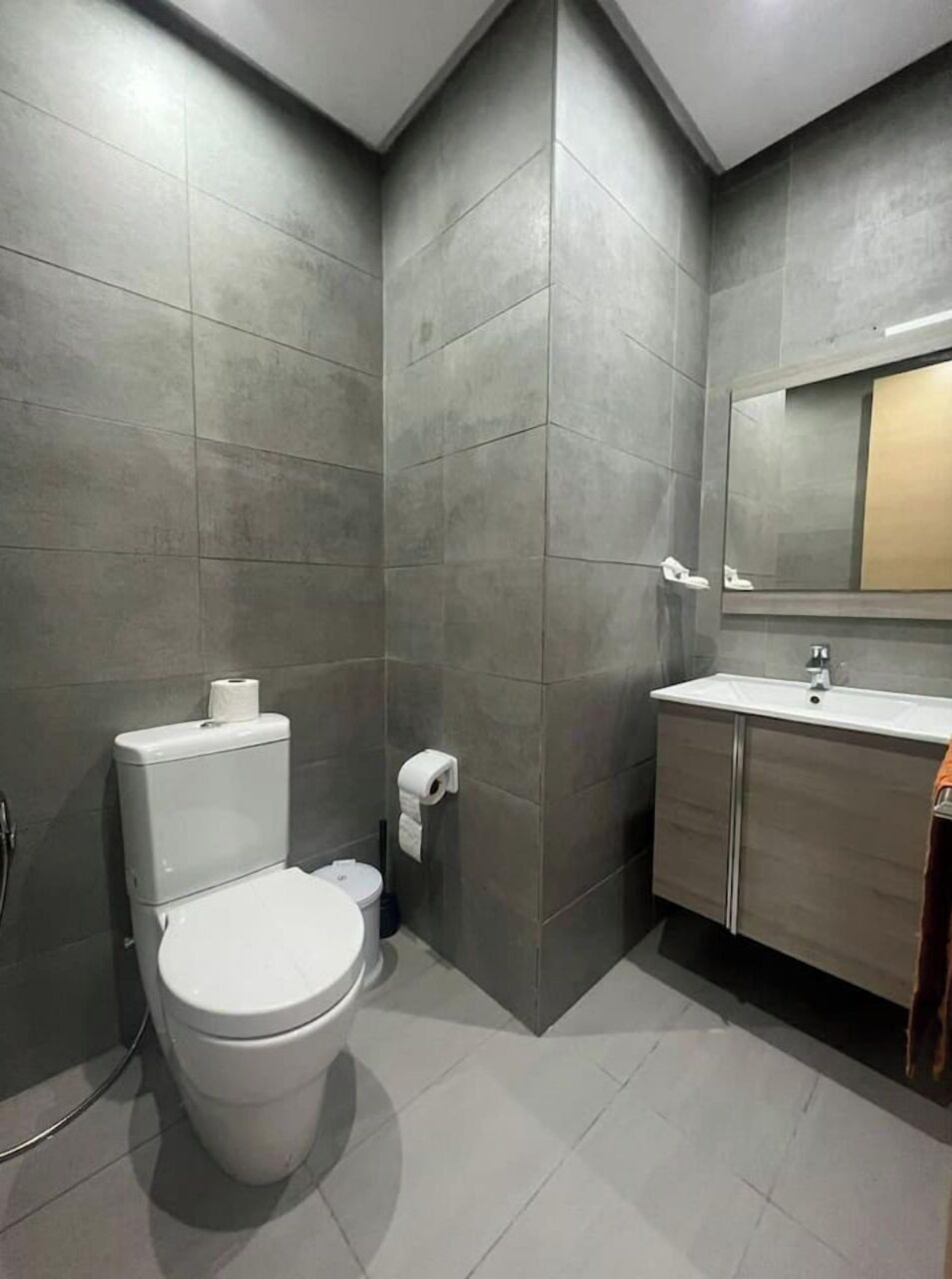 Un baño moderno con inodoro, lavamanos y espejo.