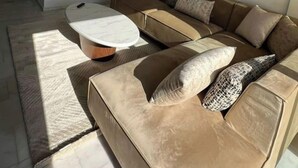 A modern living room with a sectional sofa, a round coffee table, and a unique wall-mounted circular mirror. - Shiny appartment in Prestigia (Rabat)