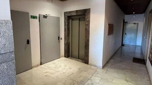 A hallway with a marble floor, wooden ceiling, and a door with a frosted glass panel. - Shiny appartment in Prestigia (Rabat)