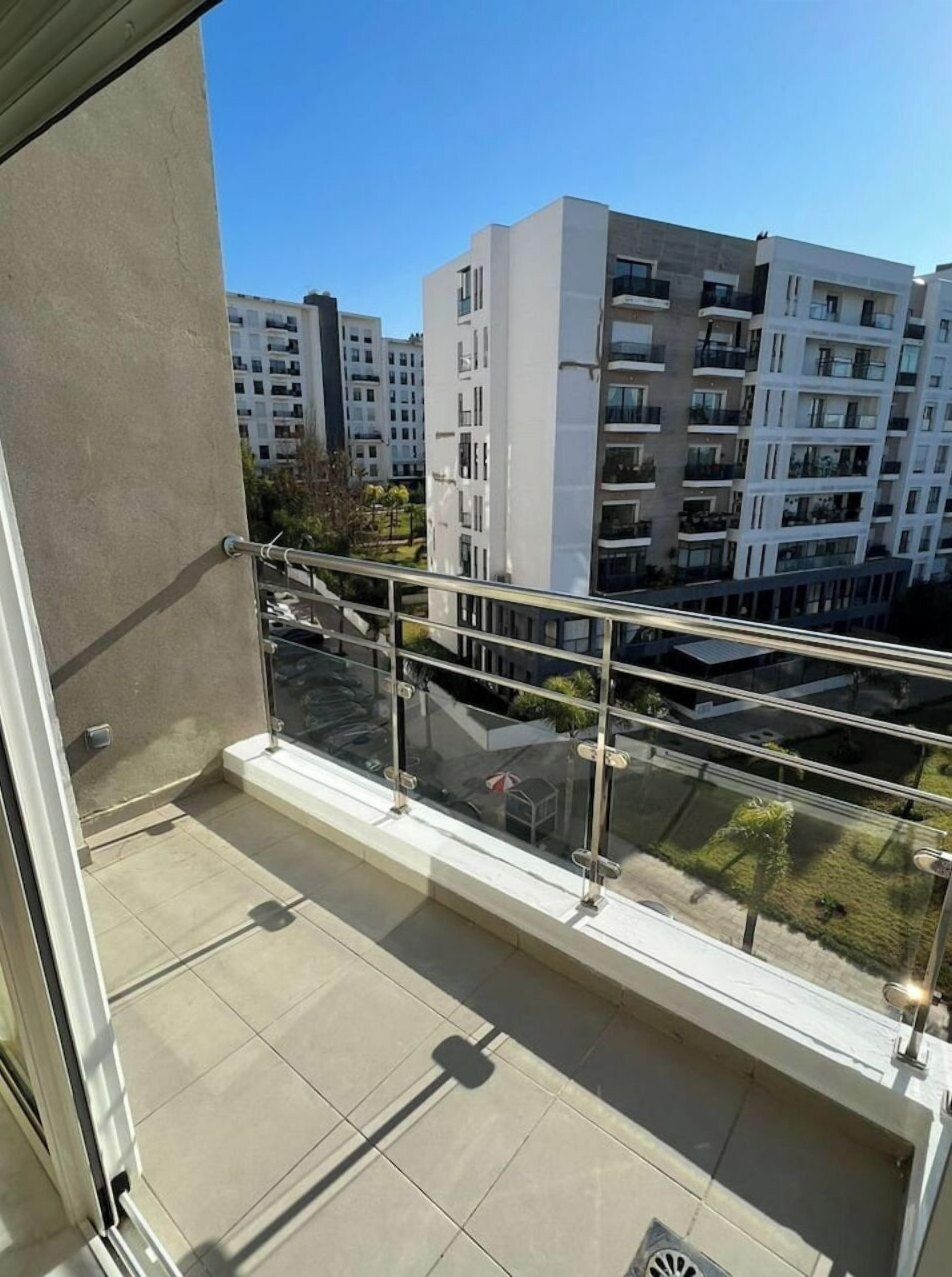 Ein Balkon mit Glasgeländer mit Blick auf ein Wohngebiet mit modernen Mehrfamilienhäusern.