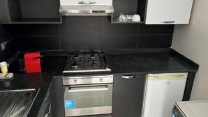 A compact kitchen with a gas stove, oven, and a built-in dishwasher. - Shiny appartment in Prestigia (Rabat)