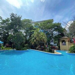 Relax by the tranquil pool surrounded by lush greenery and shaded areas.