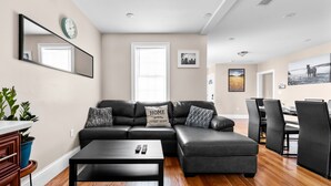 Una sala de estar moderna con un sofá modular, una mesa de centro y un comedor con sillas y una mesa.
