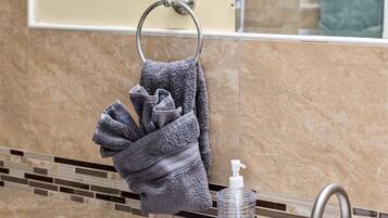 A bathroom with a sink, mirror, towel rack, and soap dispenser.