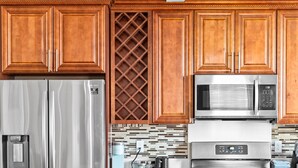 Una cocina moderna con armarios de madera, electrodomésticos de acero inoxidable y un comedor con dos sillas y una mesa.