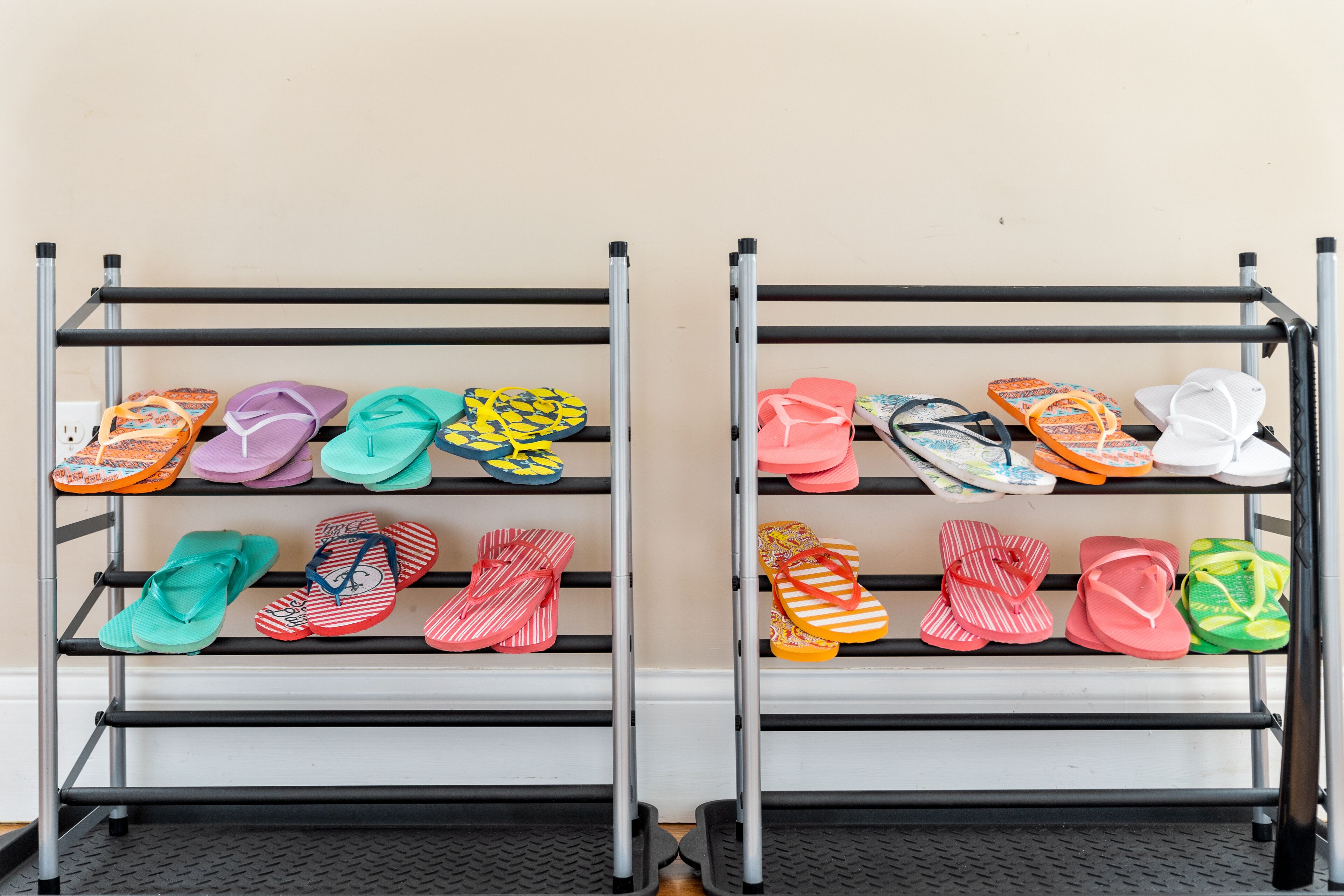 Two metal racks with multiple shelves holding colorful flip-flops.