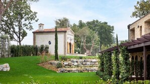 Ein gepflegter Garten mit einem Kiesweg, einem kleinen Gebäude mit Ziegeldach und einer Pergola.